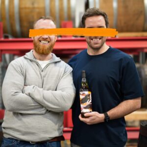 Reacted whiskey, Michael Cowman and Ronan Collins holding a bottle of whiskey